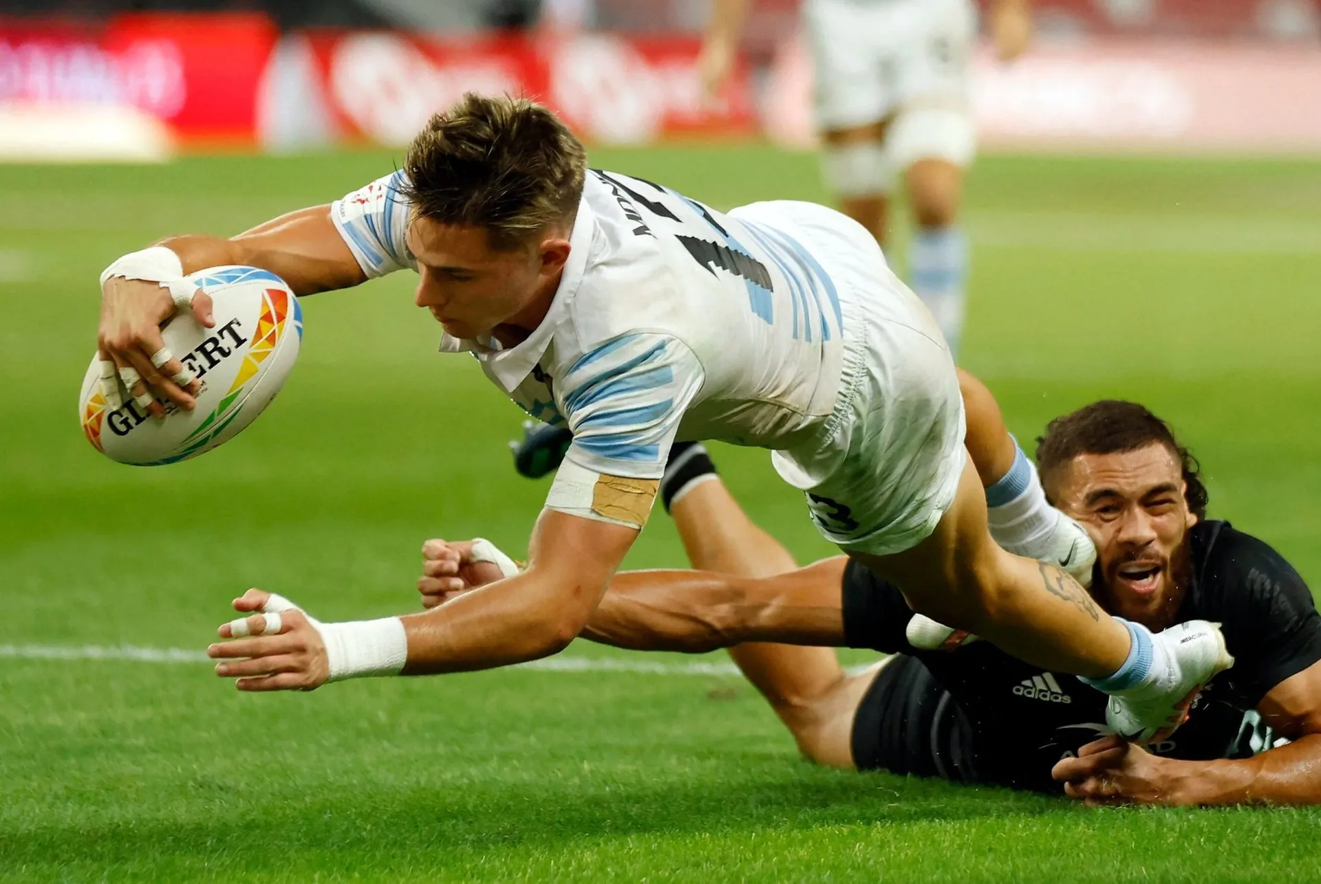 Jugadores de rugby disputan el balón bajo los focos del estadio.